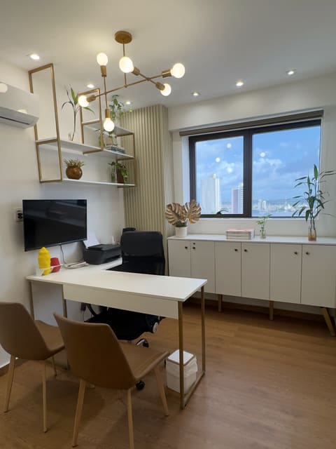 Sala de atendimento com lustre dourado, janela com vista para a cidade e poltrona de couro caramelo